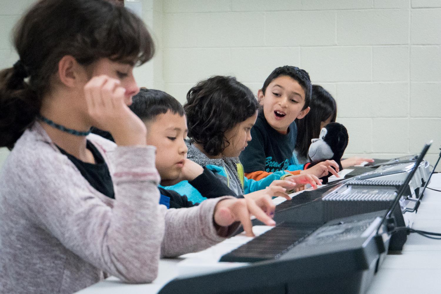 Children practicing playing keyboard pianos. 