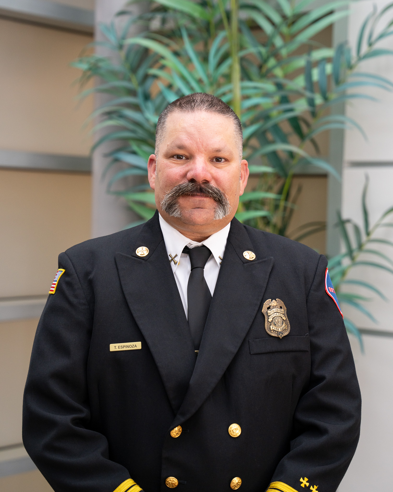Photo of Battalion Chief Travis Espinoza in Class A uniform with badge affixed to left lapel